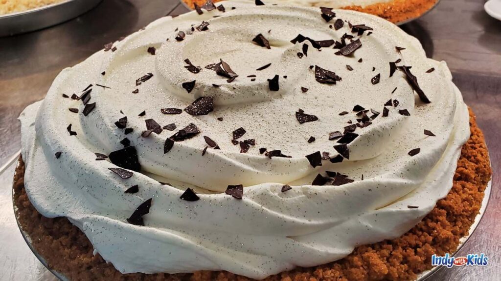 a chocolate chip pit frosted with Oreo and chocolate flakes is in the display case at cake bake shop 