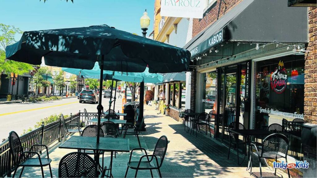 Fayrouz Mediterranean Restaurant is one of many restaurants on Main Street in the Carmel Arts & Design District. There is outdoor seating under black umbrellas on the sidewalk in front of the restaurant.