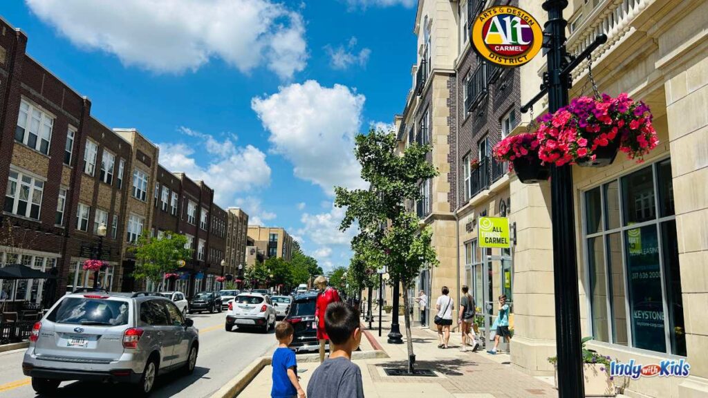 A view of the Carmel Arts & Design District with people walking on the sidewalks, shops, and al fresco dining tables