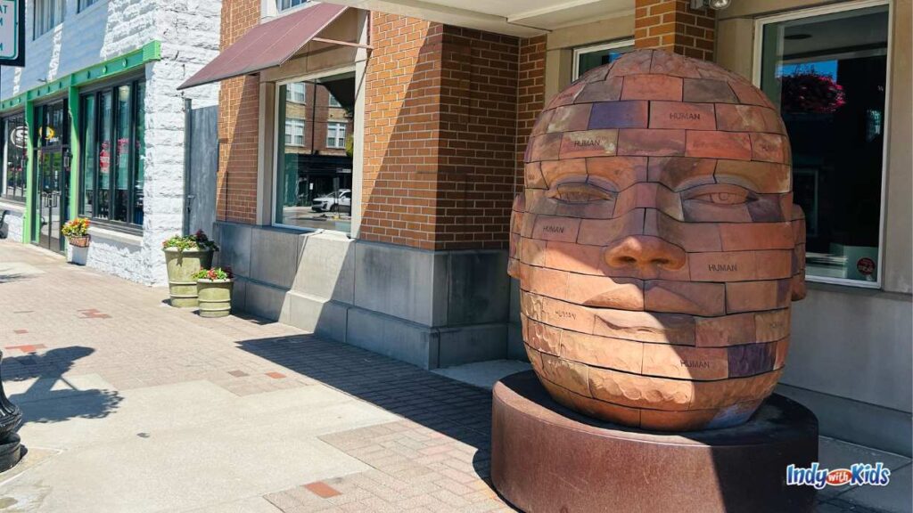 a large sculpture of a head made out of bricks sits at the entrance to an art gallery at the Carmel Arts & Design District