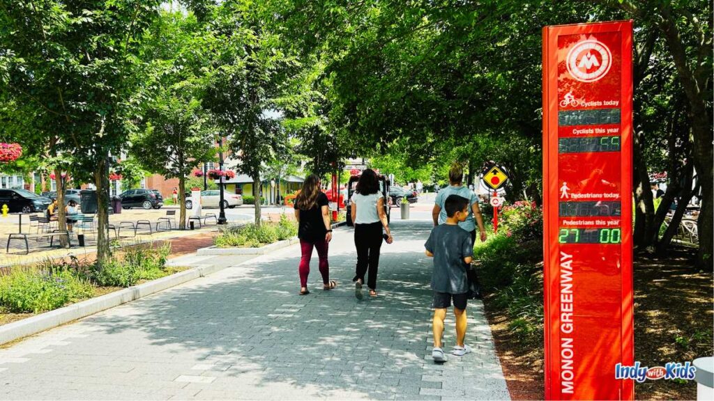 Walkers on the Monon Trail pass a red sign which displays in real time the number of people that have passed on the Monon Trail today by foot and on bike.