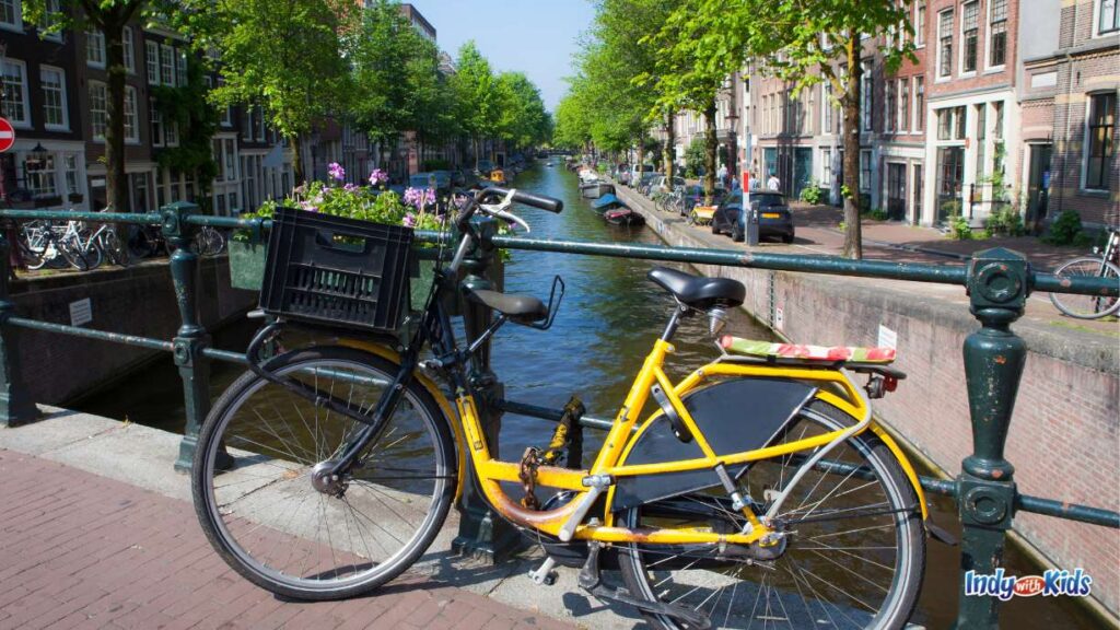 things to do in august: a yellow bike rests against a railing on a bridge over a canal