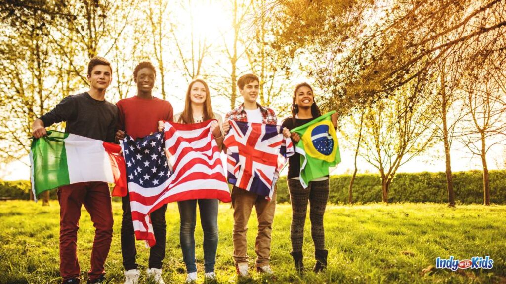 Indianapolis Events OCTOBER EDITION: five students hold up their respective flags on a grassy field with trees behind them (mexico, USA, great britain, Brazil)