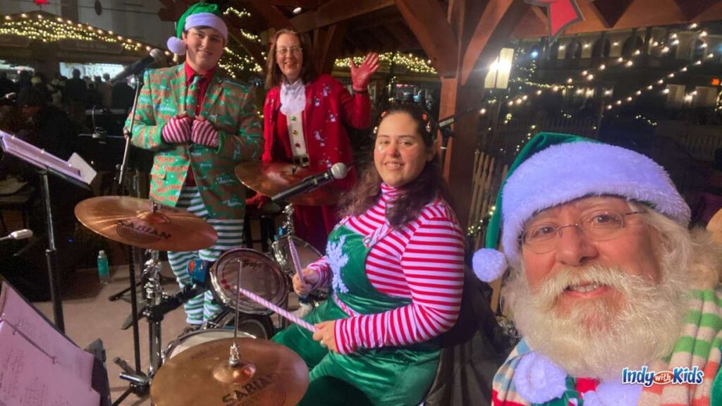 a band all dressed up in Christmas attire in front of a drum set performs at the Carmel Christkindlmarkt