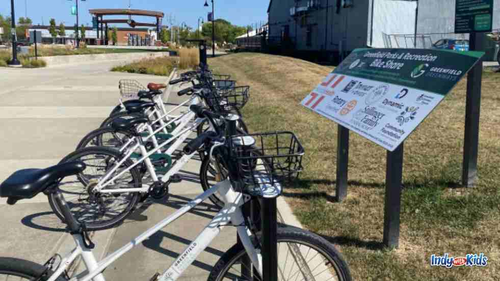 White bikes parked in front of a sign for the greenfield bike share program