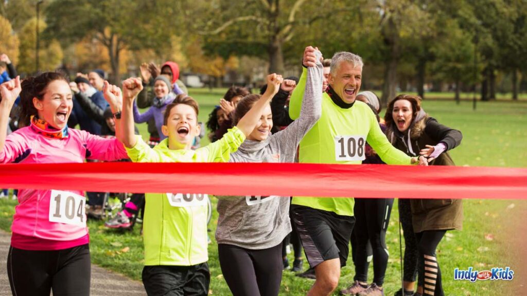 Holiday 5Ks in Indianapolis: Conquer Indy Turkey Trots & Christmas 5Ks - a family holds hands as they cross the finish line of a 5K and break the red ribbon