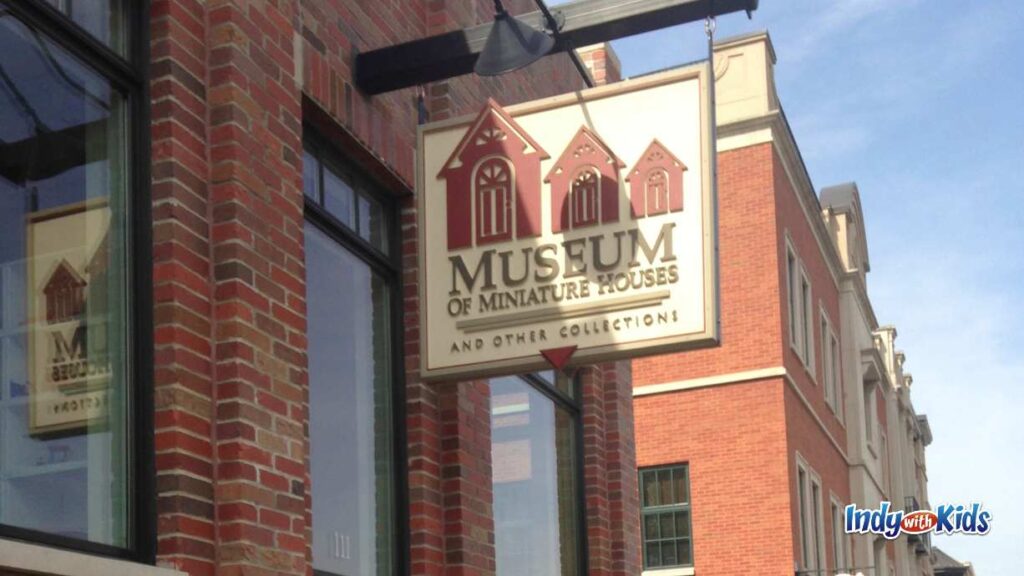 a sign hanging down from the side of a brick building reads: museum of Miniature houses