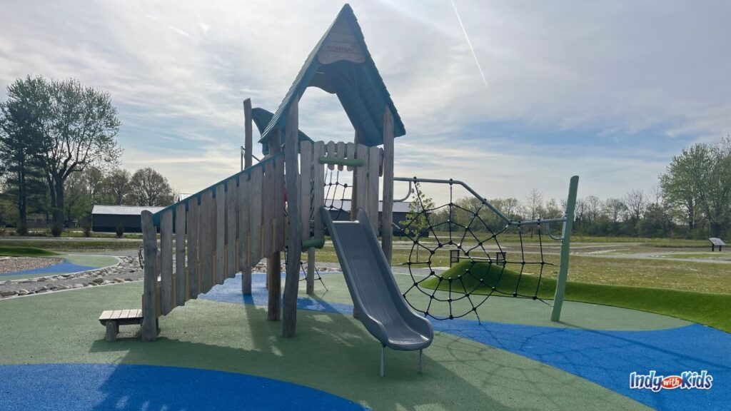 one of the wooden play structures at virgil park contains a slide and a spider web climbing feature