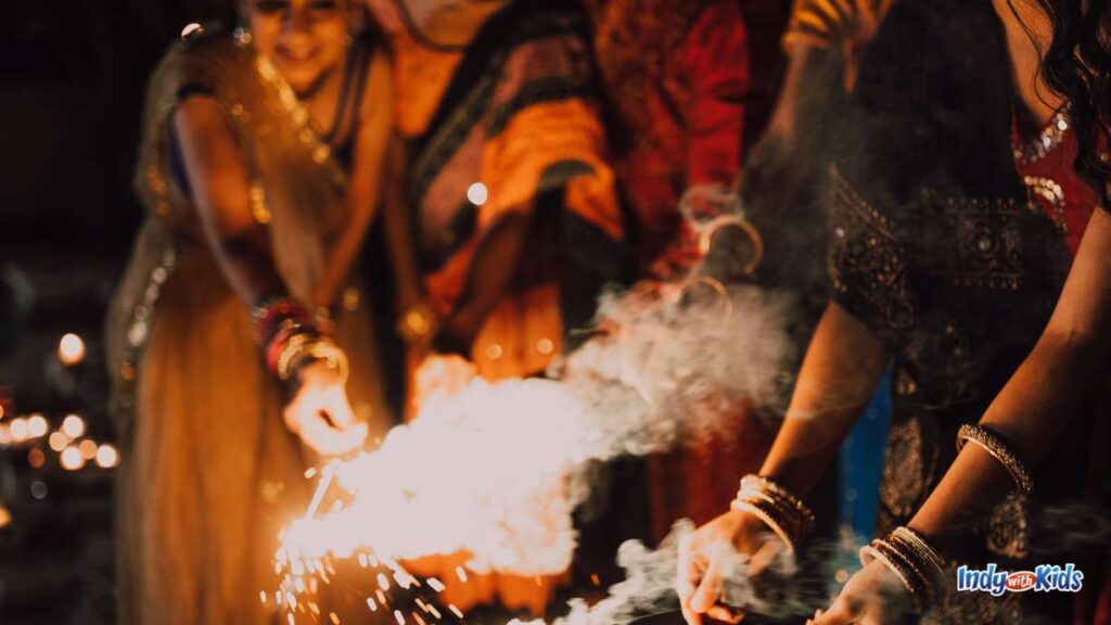 several people dressed in traditional Indian garments hold sparklers together at night for diwali