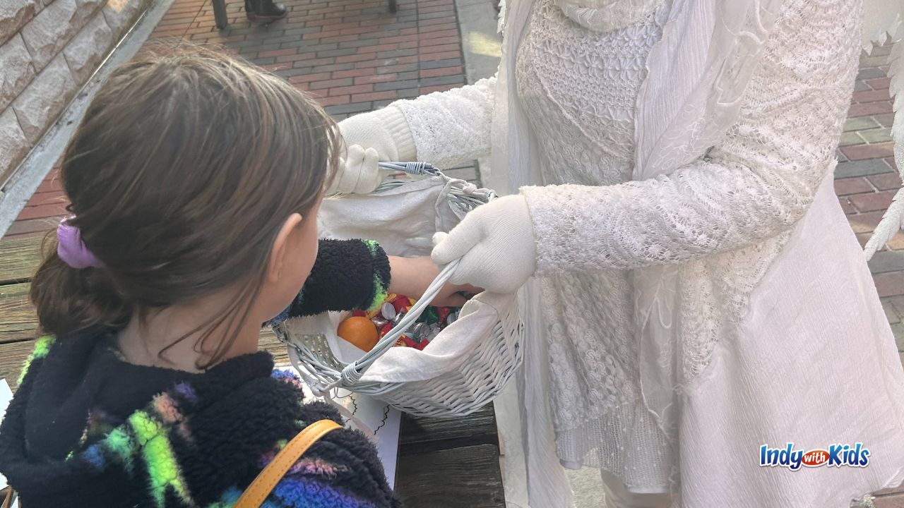 A child selects a candy from a basket offered by a costumed character at the Athenaeum Christkindlmarkt in Indianapolis.