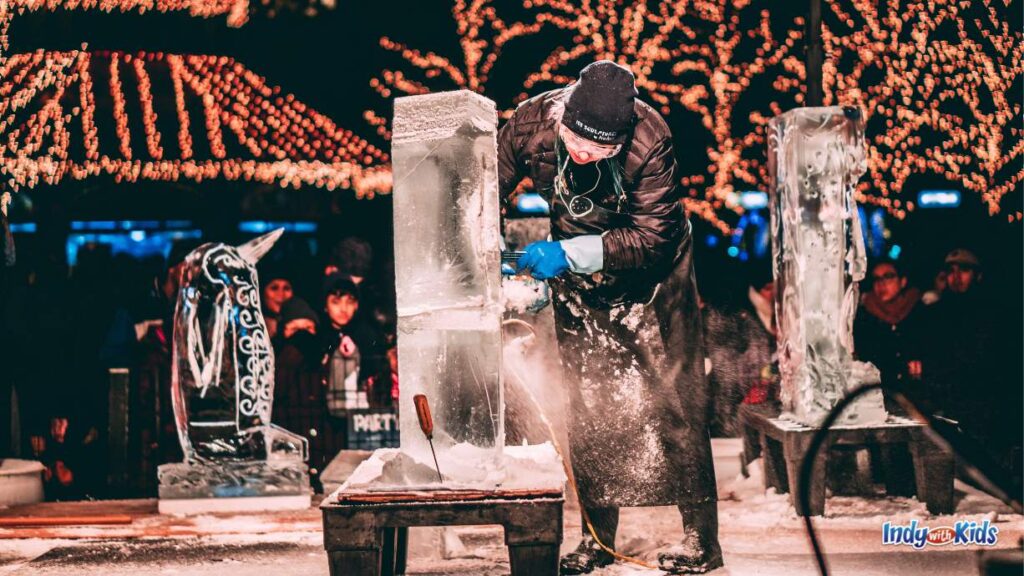 Things to Do in Indianapolis in February - an ice sculptor shaves an ice block in the evening with lit up trees in the background and other ice sculptures in the background