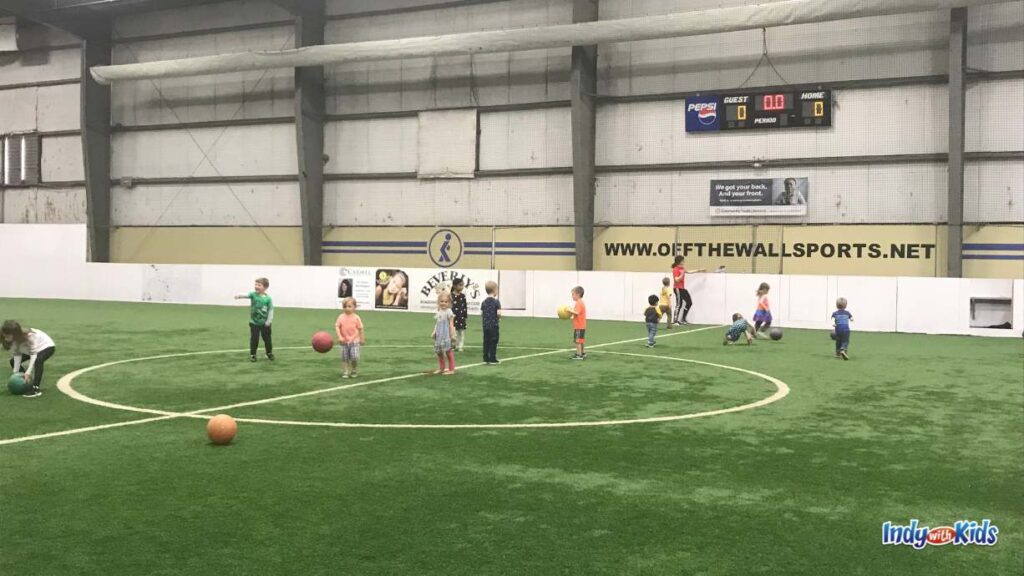 a dozen kids play on an indoor turf field at off the wall sports carmel