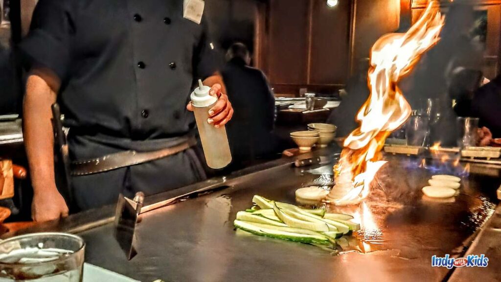 Date Night Ideas ZIONSVILLE EDITION: a hibachi chef stands behind the grill as a tall flames shoots up over chopped up vegetables