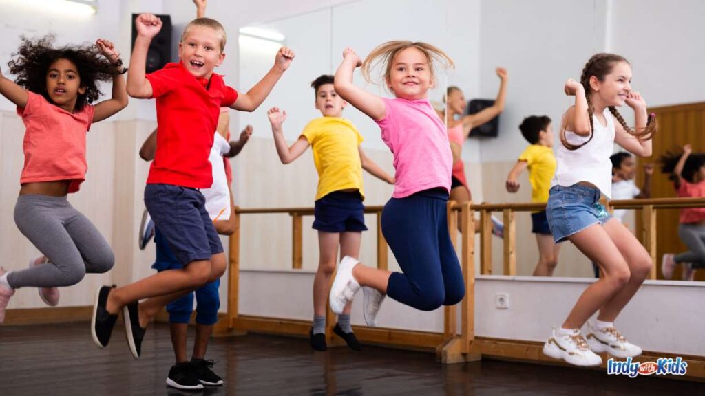 Spring Break Camp Indianapolis: kids in a dance class with a mirrored wall jump in the air in unison