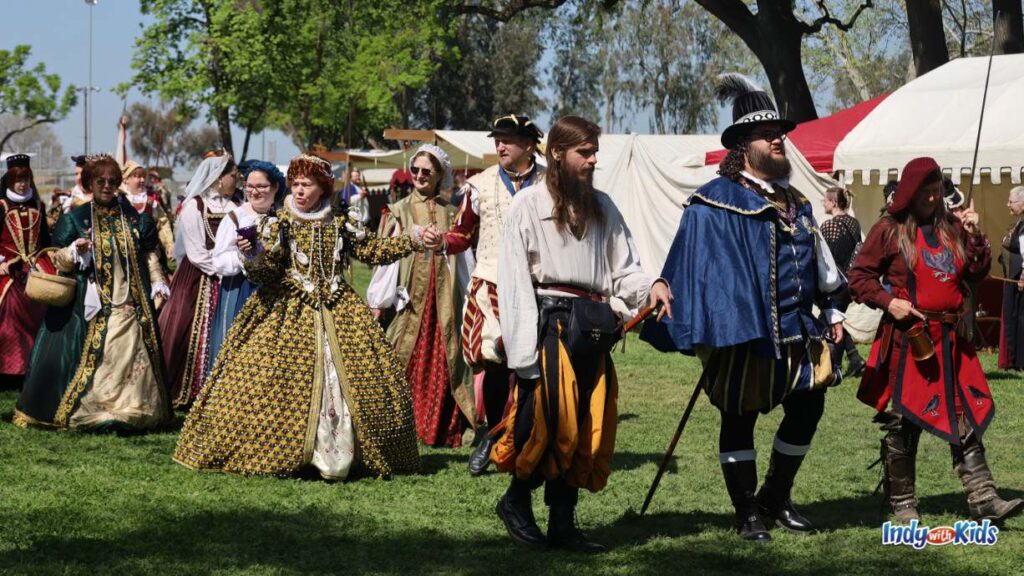 adults dressed up like Renaissance characters gather in a grassy park