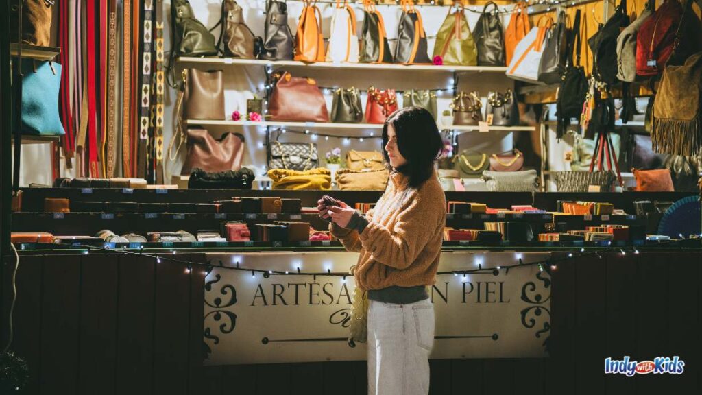 a woman inspects an item from an artesan vendor selling women's clothing and jewelry