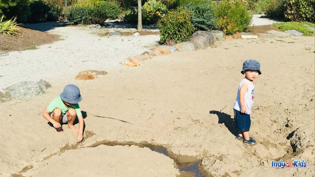 two little boys play in a giant sand Play area at coxhall gardens