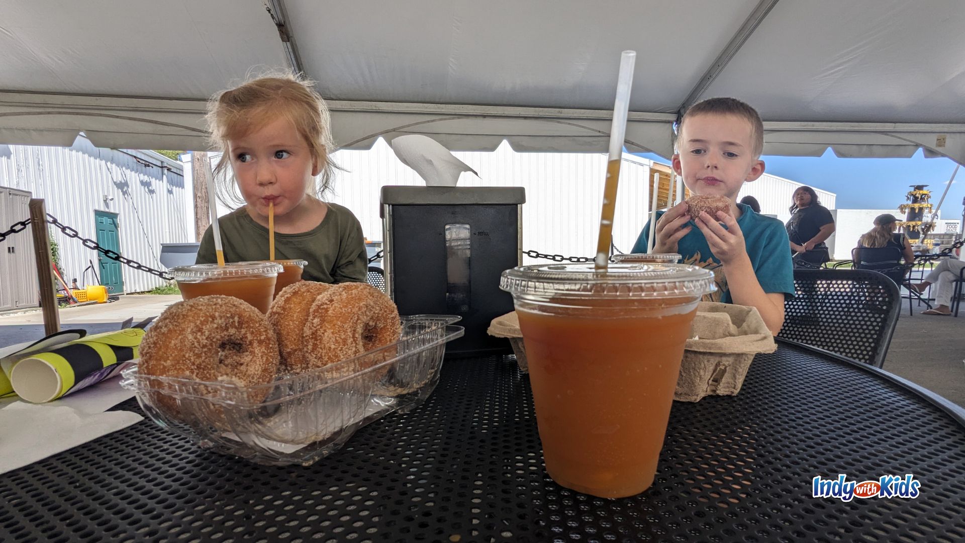 Two children snack on donuts and apple cider slushies at Tuttle Orchards in Greenfield.