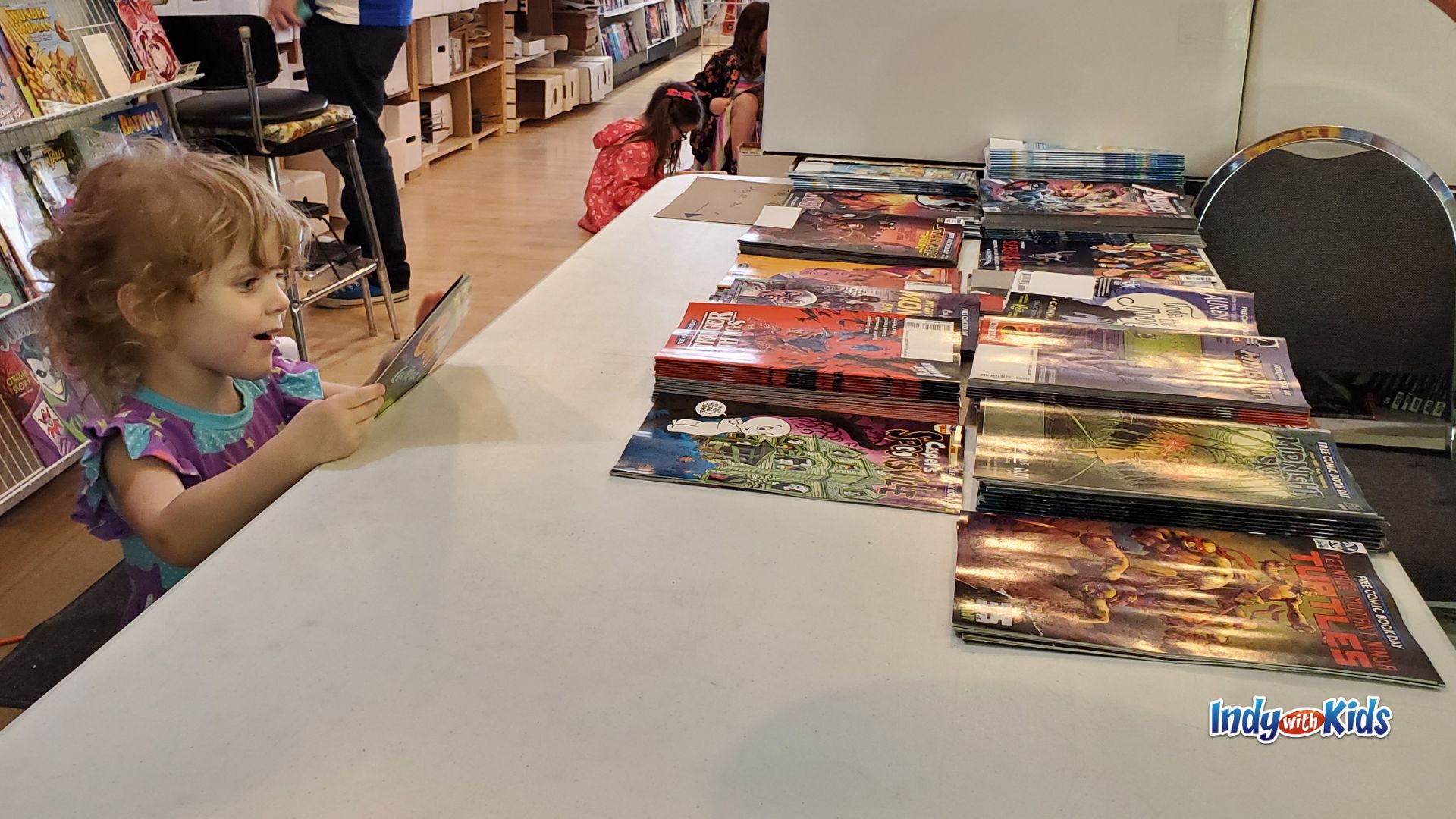 Young child looking at free comic books on a table during Free Comic Book Day in Indianapolis