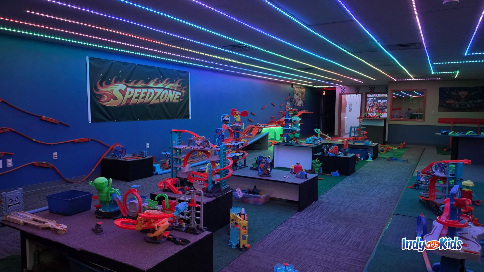 Wide view of SpeedZone indoor play space in Martinsville with Hot Wheels tracks, glowing LED ceiling lights, and race-themed decor.