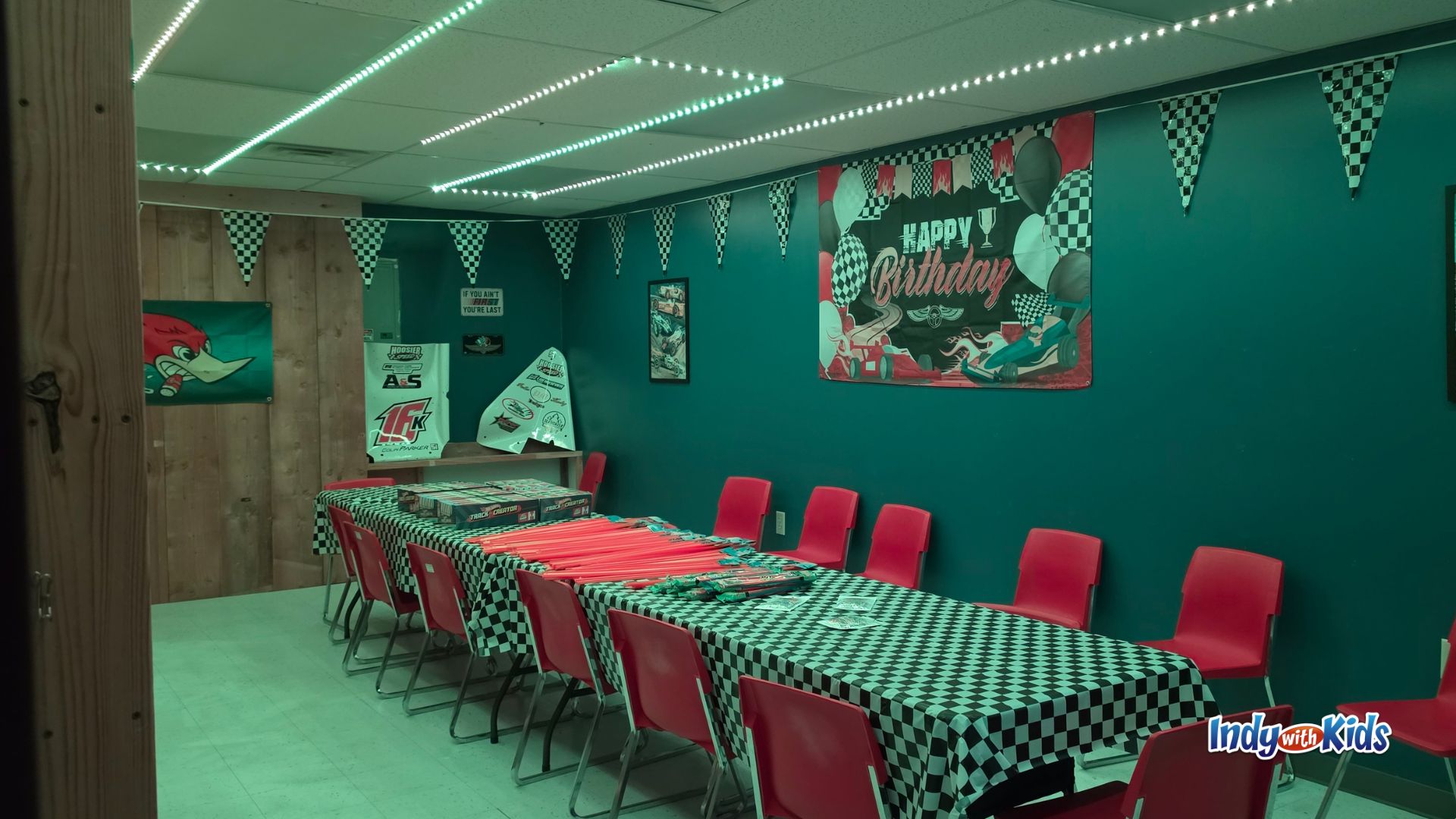 Race-themed birthday party room at SpeedZone with checkered tablecloths, red chairs, and birthday wall decor.