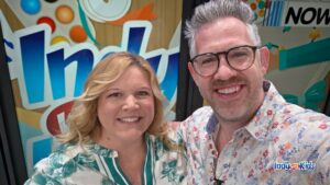 Katy Mann from Indianapolis with Kids and show host Ryan Ahlwardt take a selfie in front of a colorful Indy Now television studio backdrop after sharing Indianapolis family activity ideas.