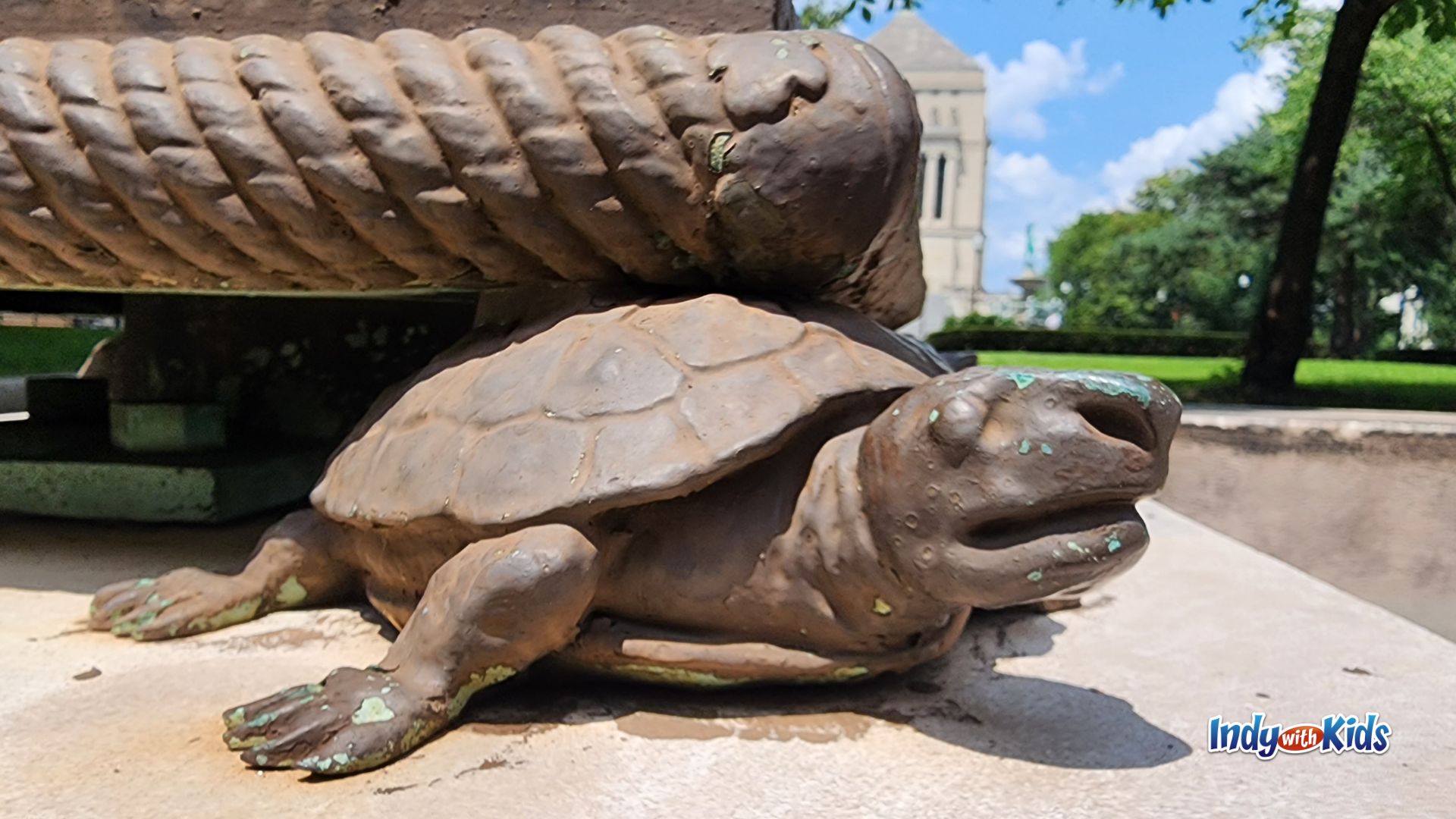 Close-up of a bronze turtle sculpture beneath an oversized bronze bread loaf, one of the whimsical public art details discovered on a downtown Indianapolis walking tour designed for children.